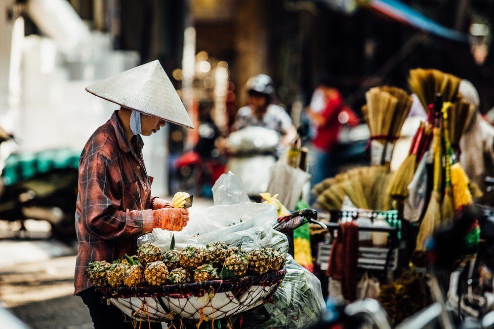 Silhouette of a man in the national Asian hat. Street vendor with a cart on the street. with pineapple tray
