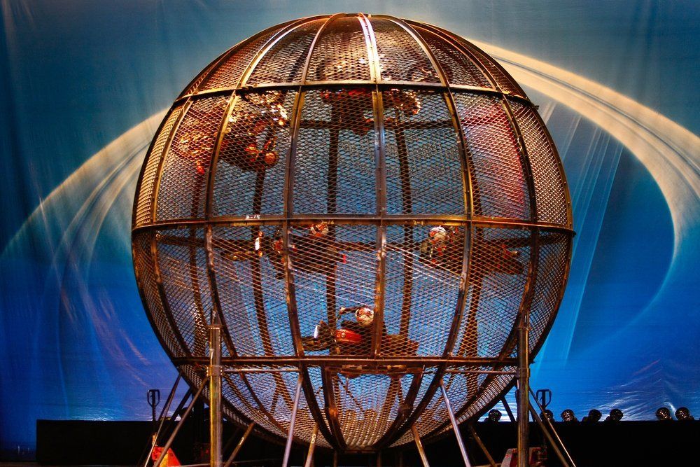 China Acrobatics Troupe Artists inside a cage racing bikes