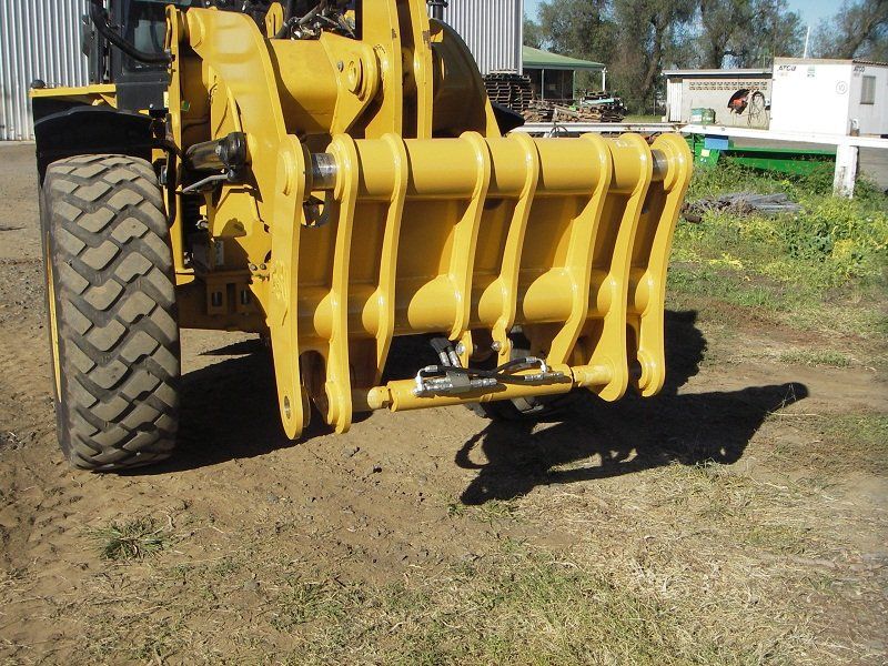 A yellow tractor is parked in a dirt field
