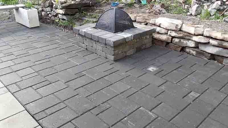 Terrasse en briques grises avec foyer extérieur en briques et mur de soutènement.