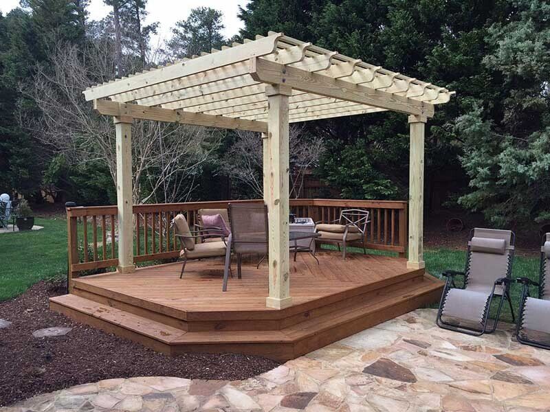 Pergola en bois avec terrasse, entourée de chaises et d'aménagements paysagers.