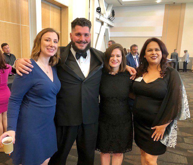 A group of people posing for a picture including a man in a tuxedo