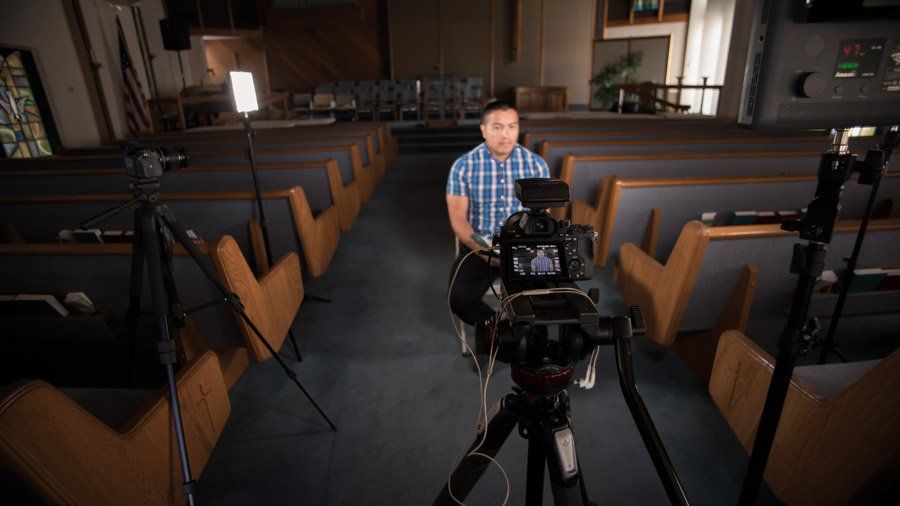A man is sitting in front of a camera in a church