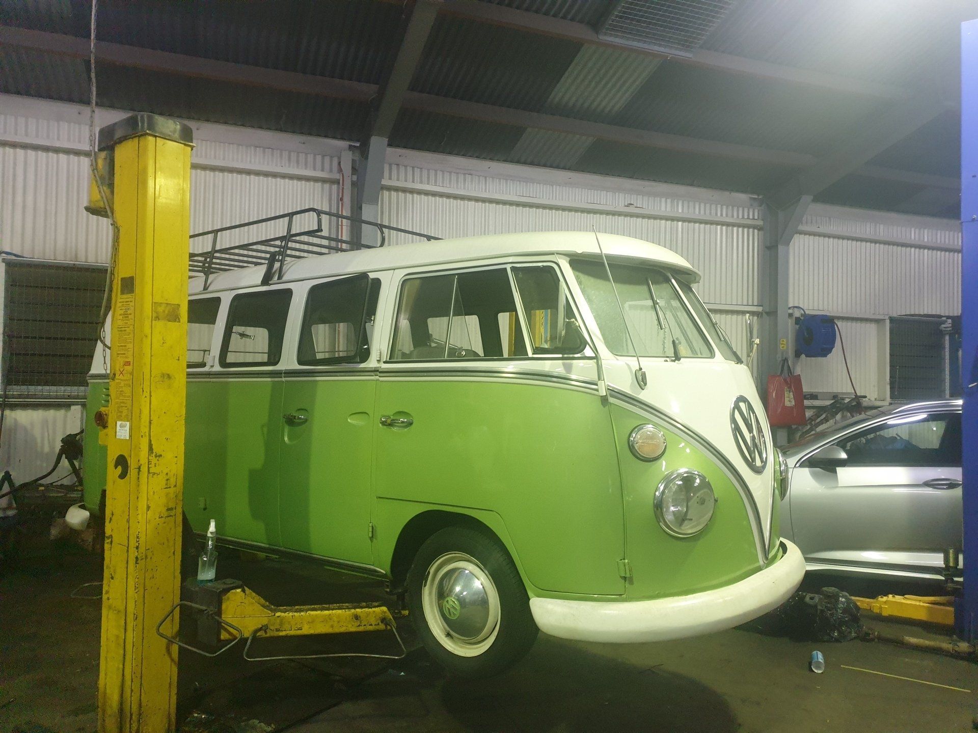 A green and white van is on a lift in a garage - Specialist Mechanics in Cairns, QLD