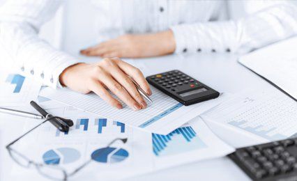 Lady sitting at a table with sheets of figures, graphs and calculator