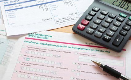 A pen on a HM Revenue and Customs form in front of a calculator