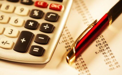 Red pen and cream calculator on sheets of figures