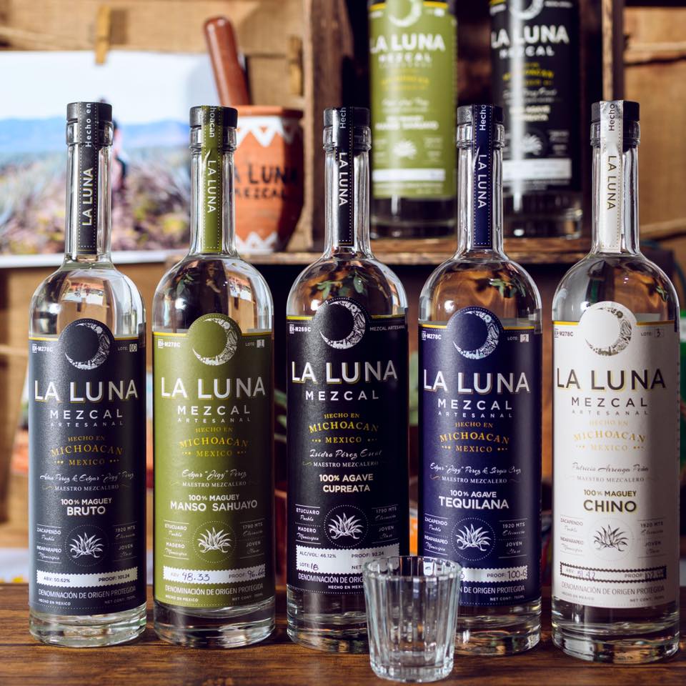 Several bottles of la luna mezcal are lined up on a table