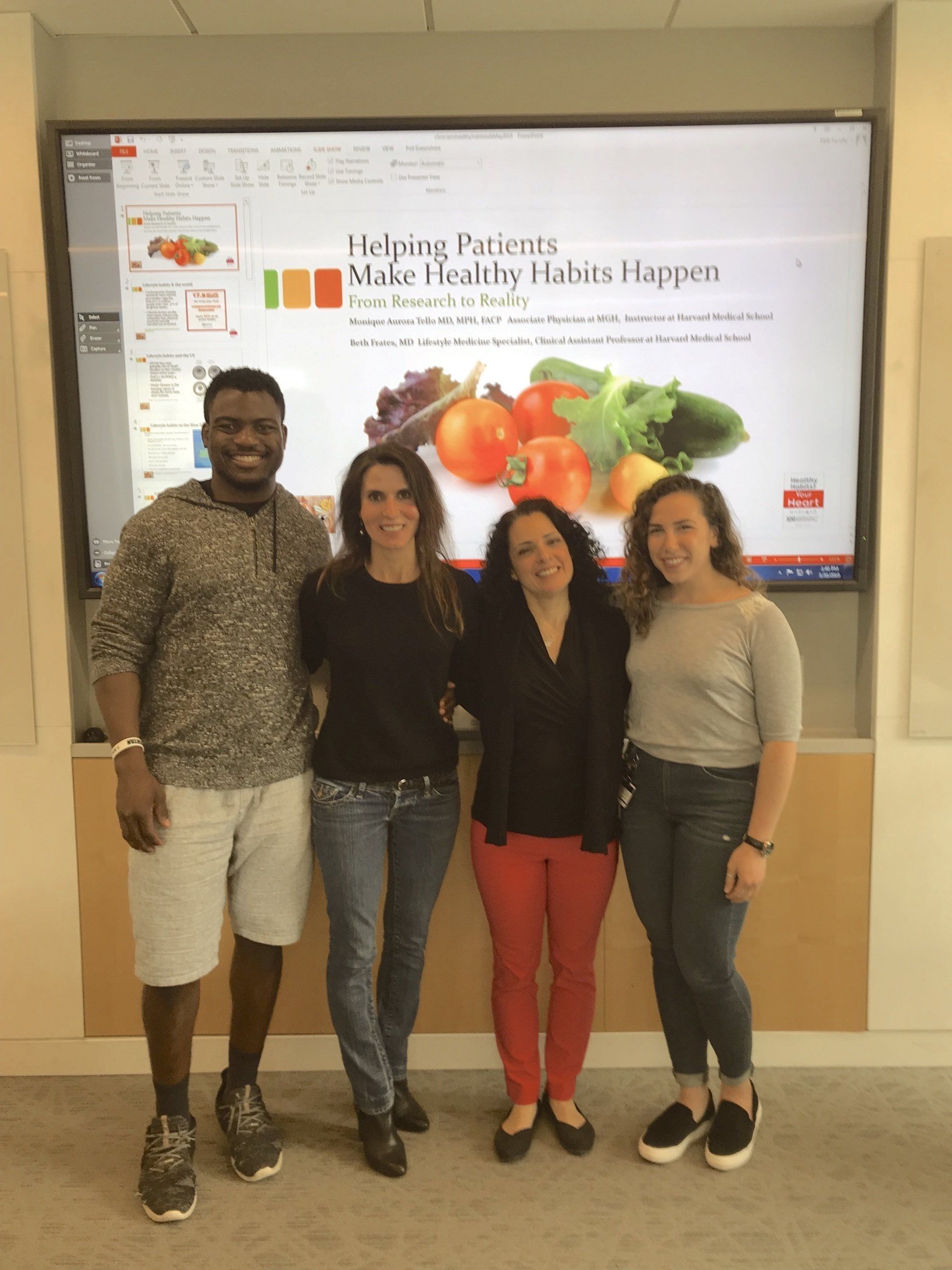 Four people stand in front of a screen displaying fresh produce. The screen title reads