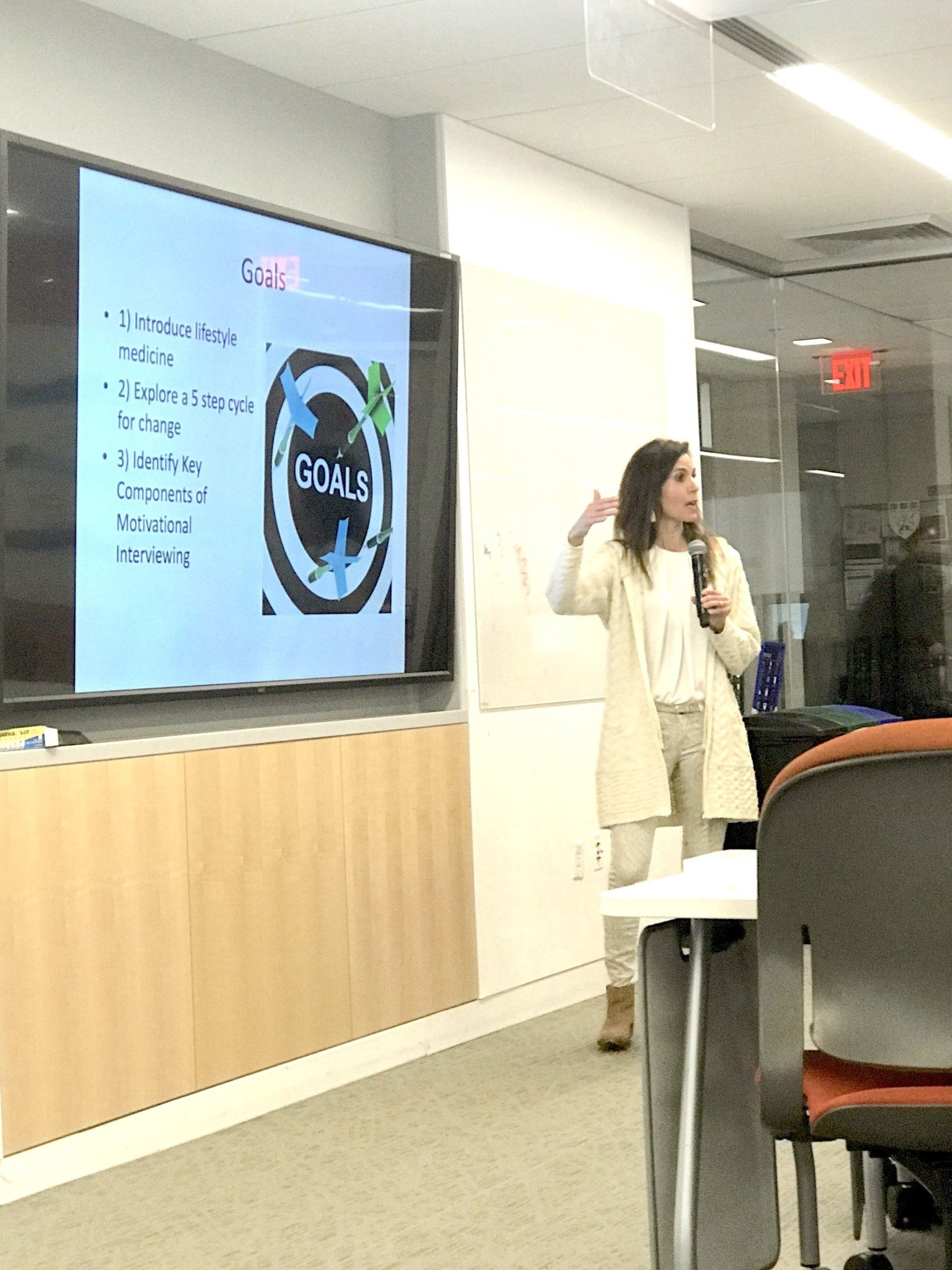 Woman presenting at a screen displaying the word 