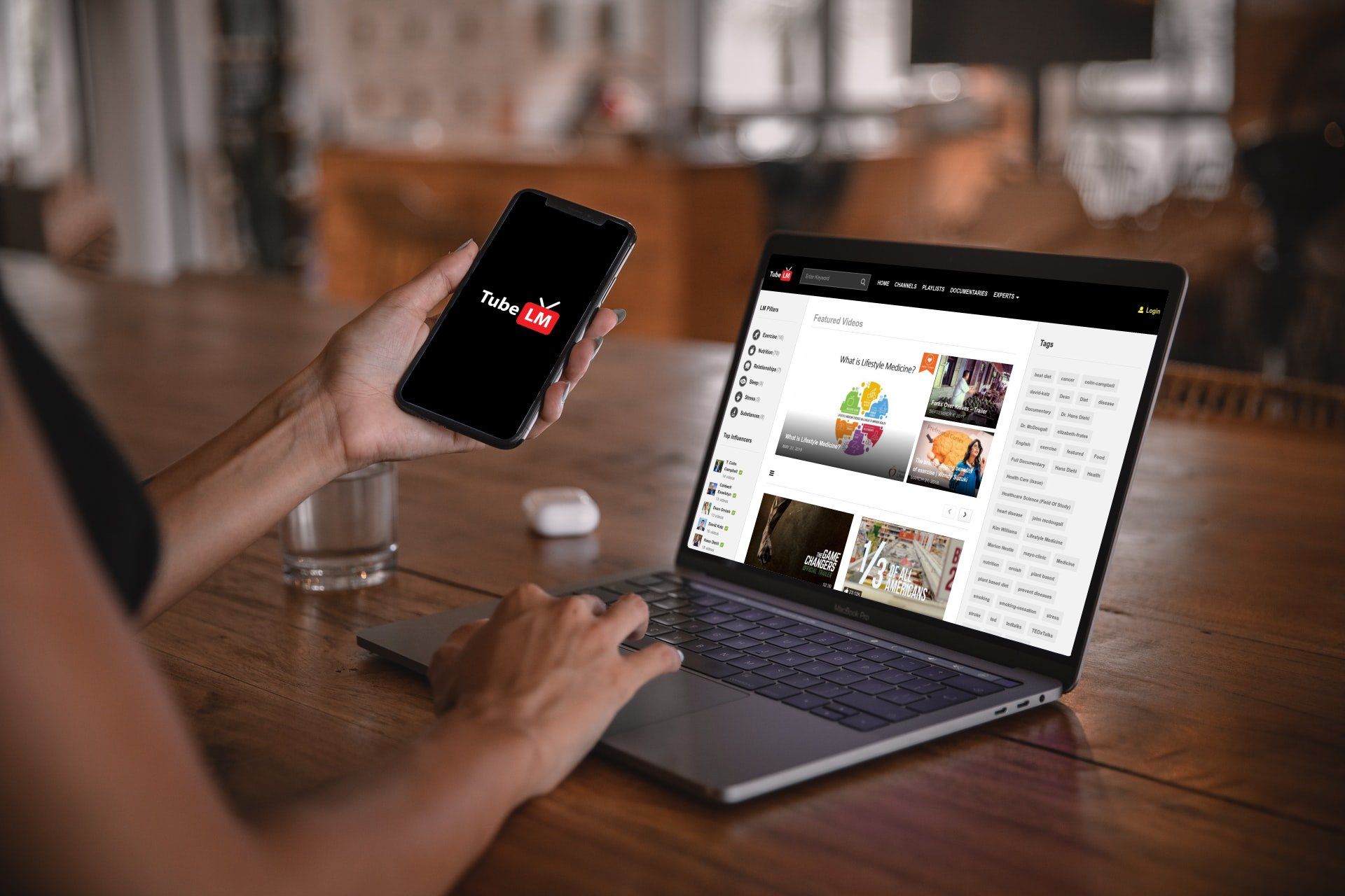 Person using a laptop and holding a smartphone, both displaying a YouTube interface.