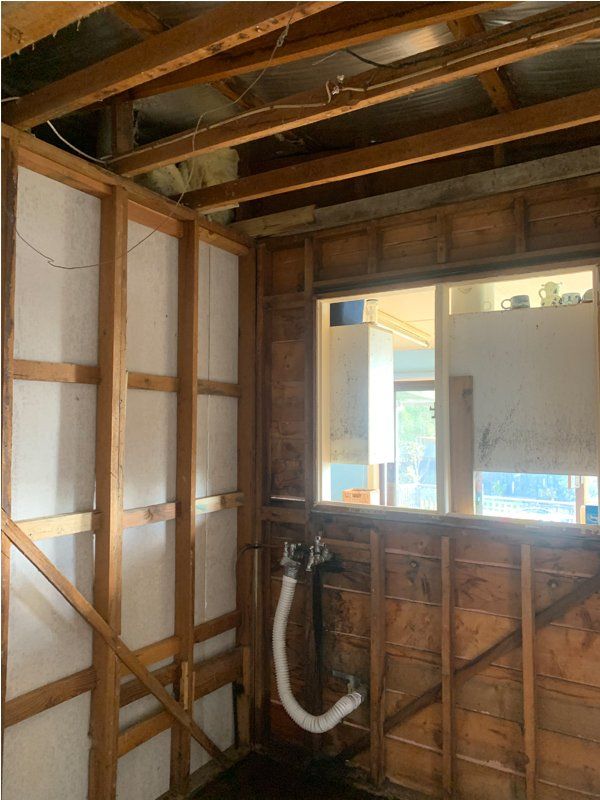 Interior wall framing, raw wood, with a window and exposed plumbing.