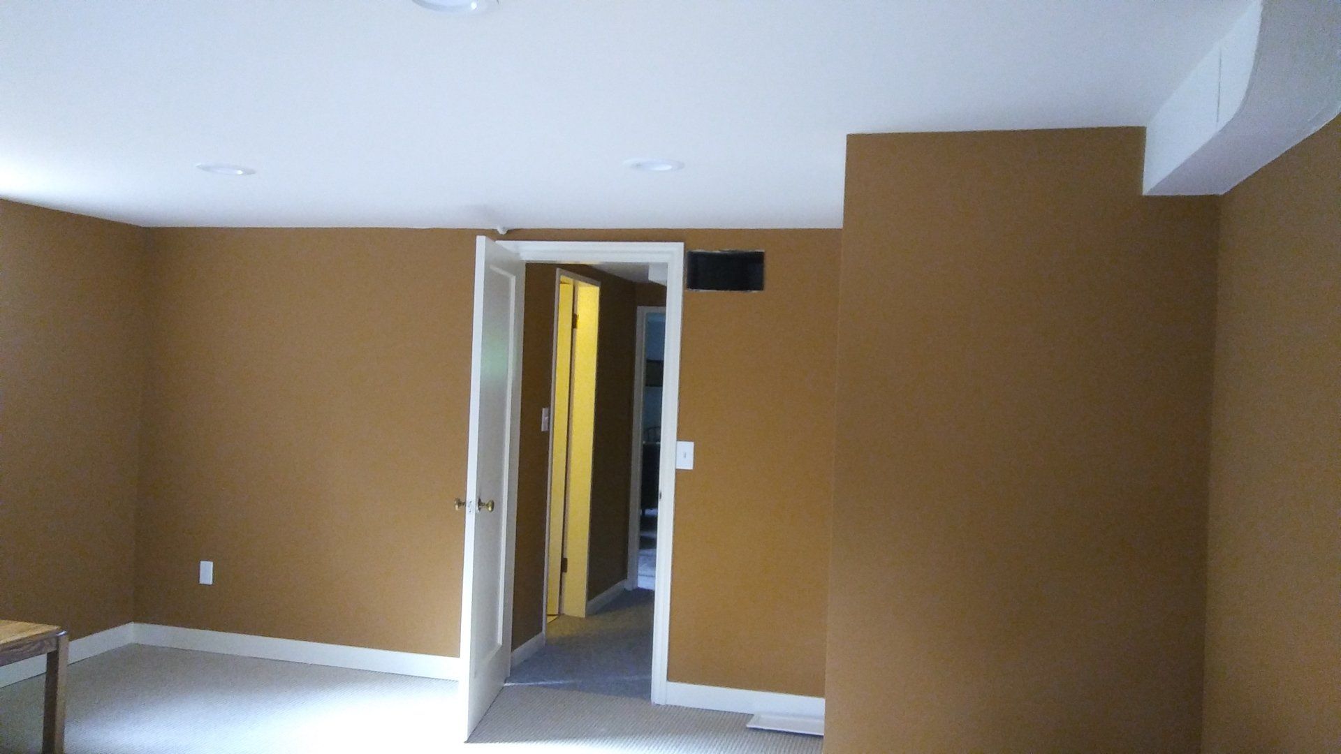 Empty room with tan walls, white ceiling, and an open doorway to a hallway.