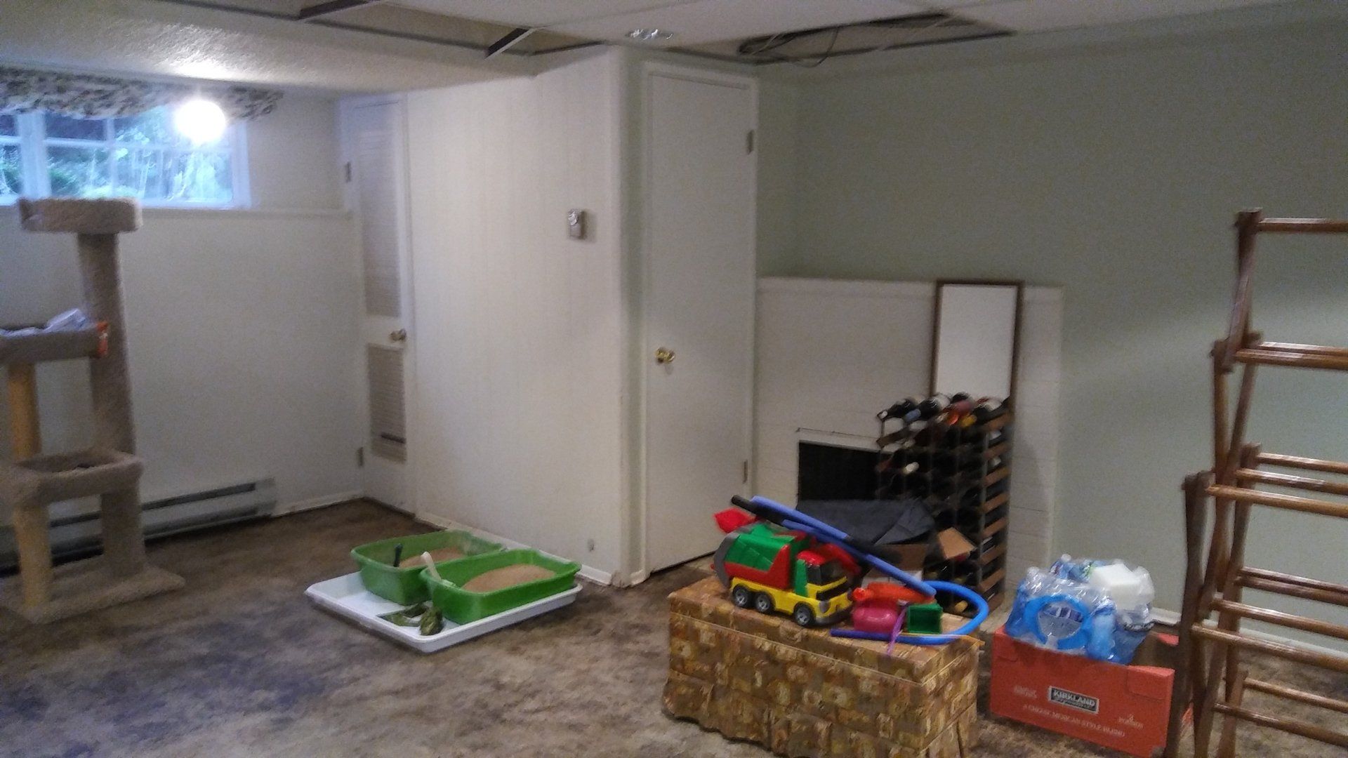 Basement playroom with toys, baskets, and shelves against white walls and concrete floor