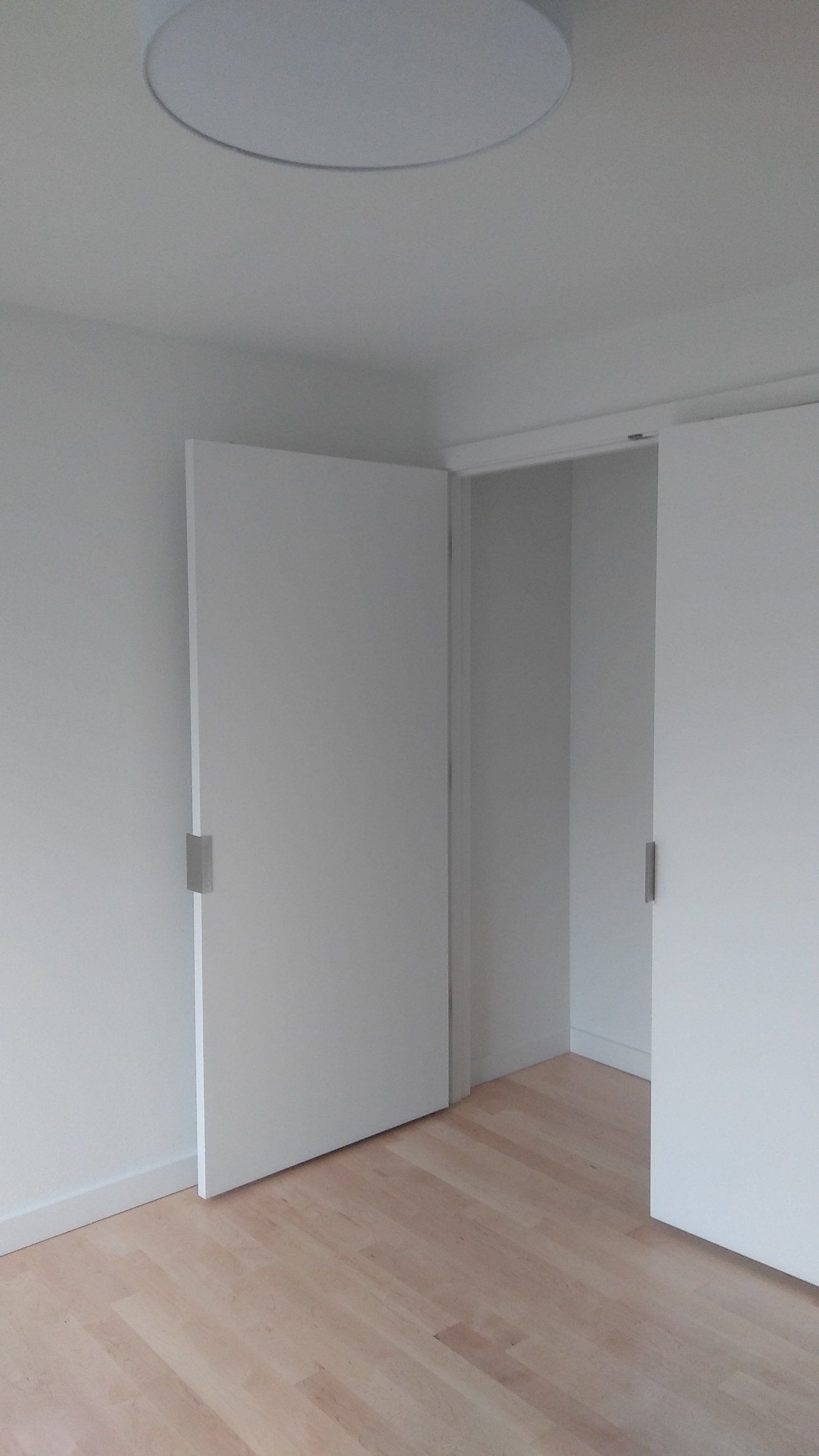 Empty white room with light wood floor and an open door leading to a hallway