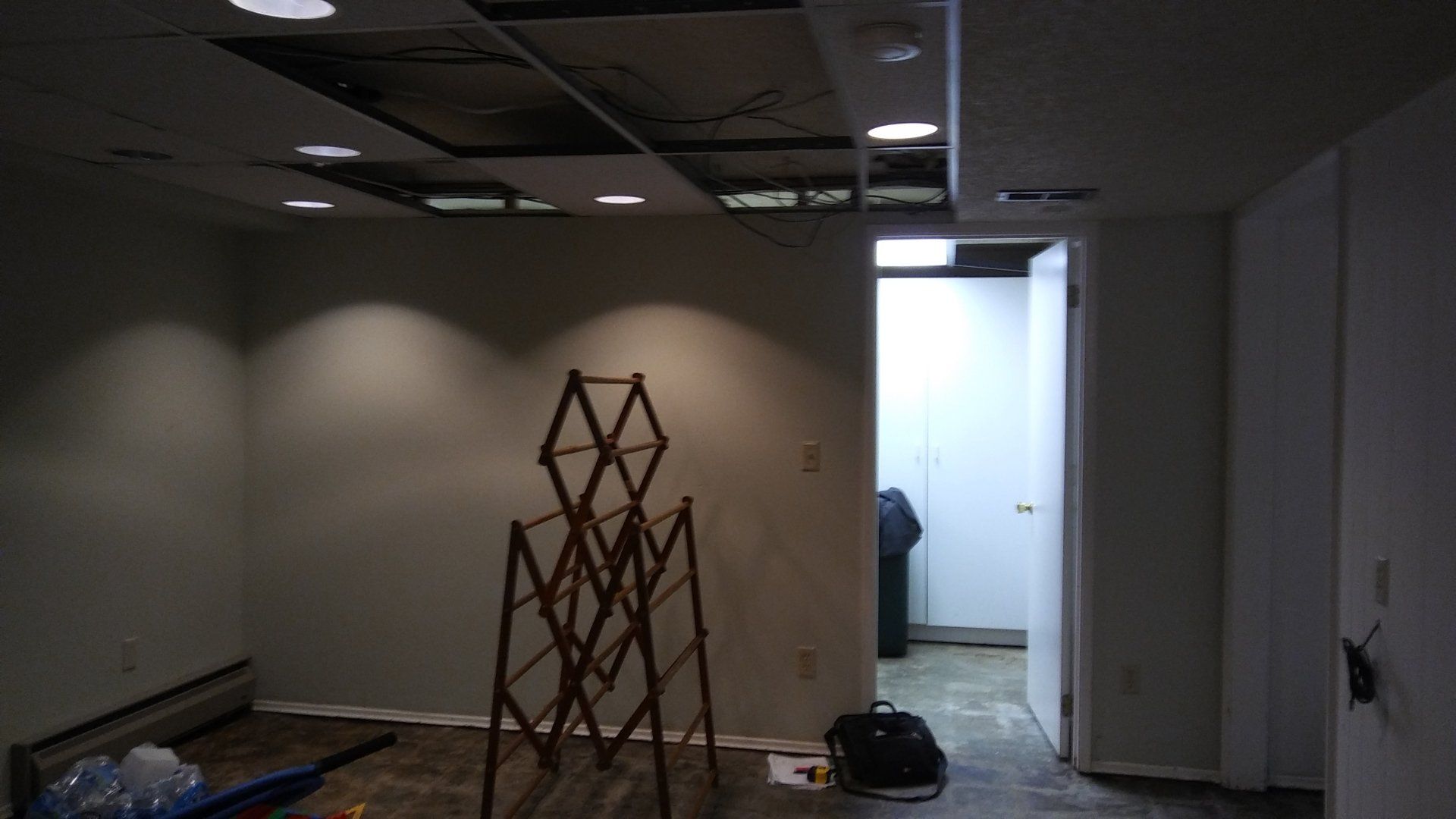 Dim office hallway under renovation with a wooden scaffold, open doorway, and construction materials on the floor