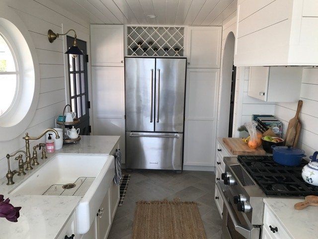 Bright modern kitchen with stainless steel fridge, white cabinets, island sink, and gas stove.