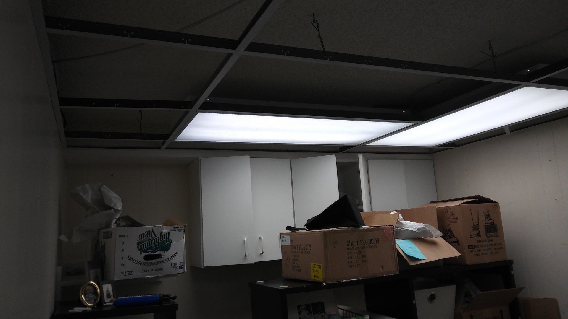 Dim storage room with boxes stacked beneath fluorescent ceiling lights
