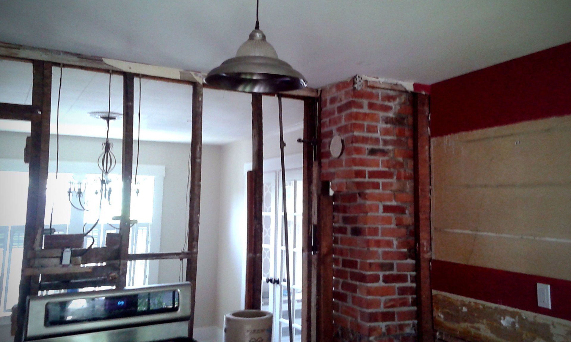 Partially renovated room with exposed brick wall, hanging light, and window framing tools