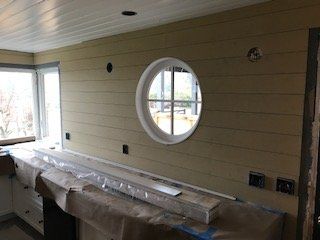 Interior kitchen wall with circular window, beige paneling, and countertops covered in plastic sheeting
