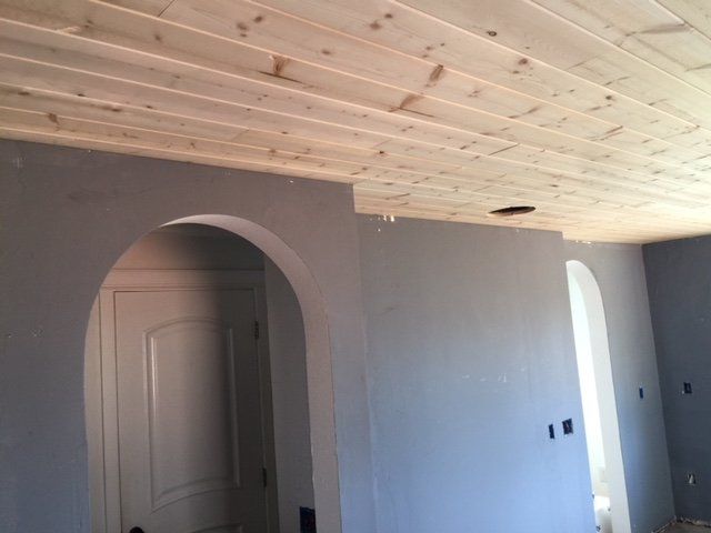 New white wood-paneled ceiling in a room with arched doorway and gray walls