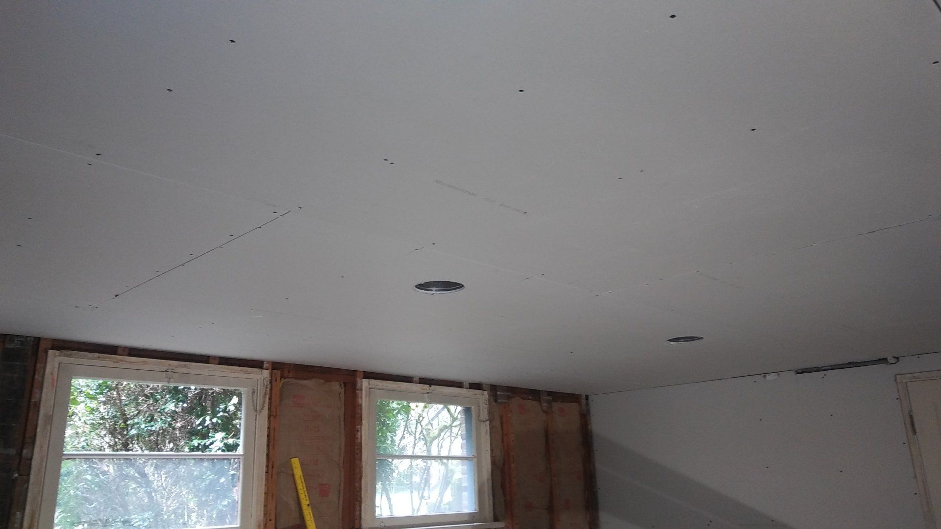Partially finished room with bare ceiling, two windows, and exposed framing near the wall