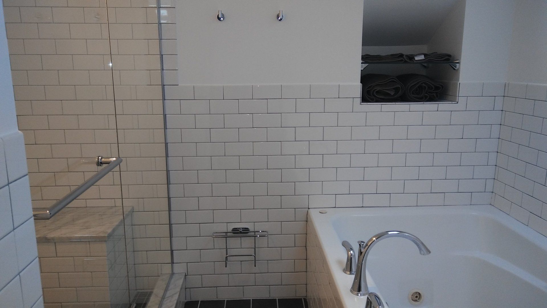 Bathroom with white subway tile, bathtub, and tiled shower area with grab bar