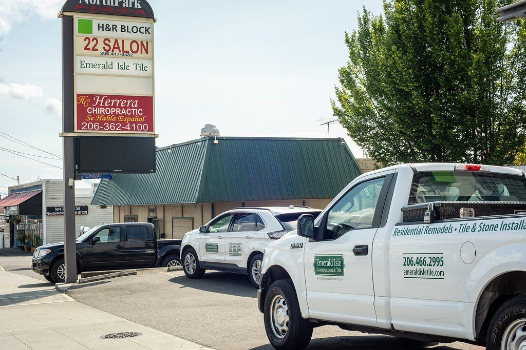 White service trucks parked beside a salon sign in a sunny lot.