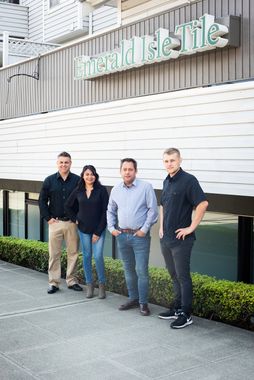 Four people standing outside a building with a green sign above them
