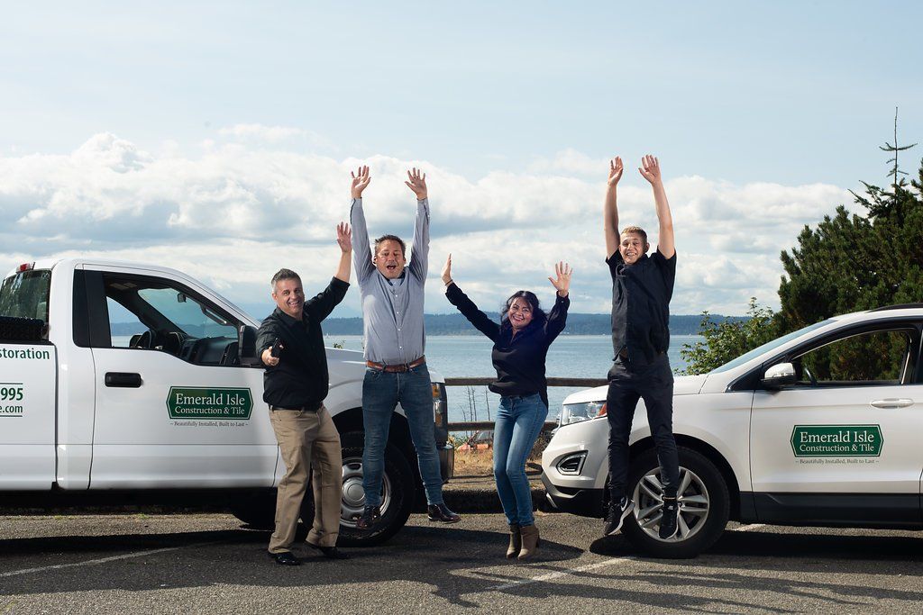 Four people cheering between two white service vans under a cloudy sky
