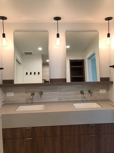 Modern bathroom vanity with double sinks, large mirrors, and warm pendant lighting