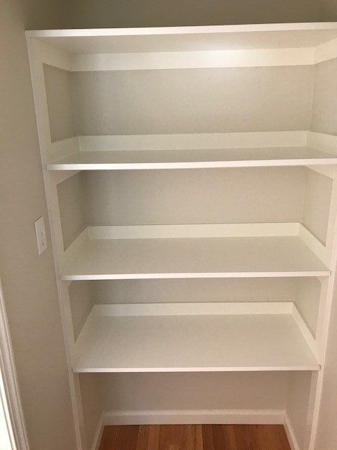 Empty built-in white shelving niche in a closet or pantry.