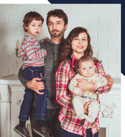 A family is posing for a picture in front of a fireplace.