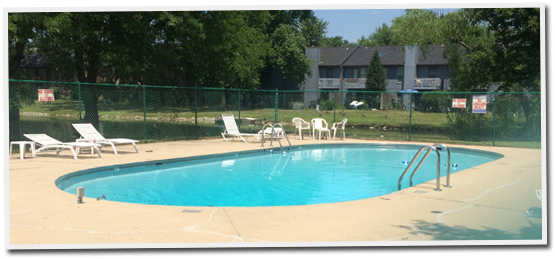 A large swimming pool surrounded by chairs and a fence