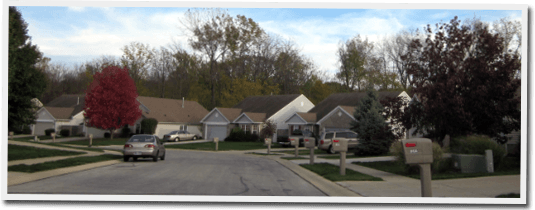 A car is driving down a street in a residential neighborhood