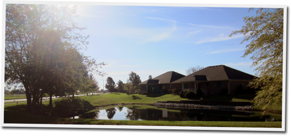 A picture of a house with a pond in front of it