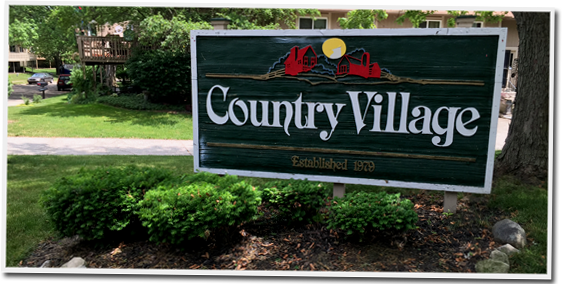 A green sign that says country village on it