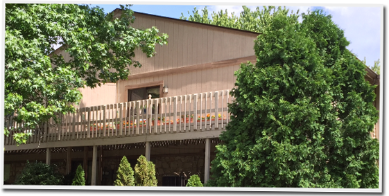 A large house with a balcony and trees in front of it.