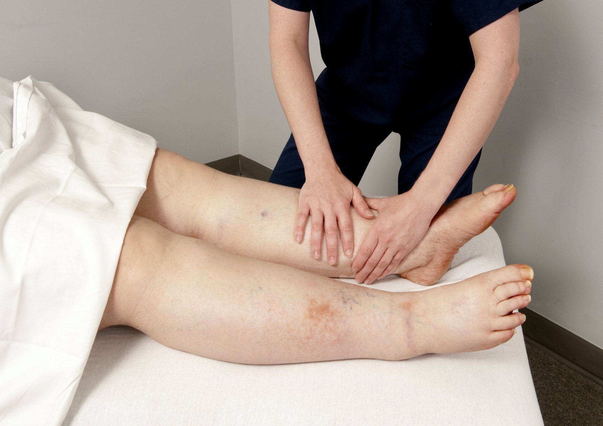 A woman is giving a leg massage to a patient.