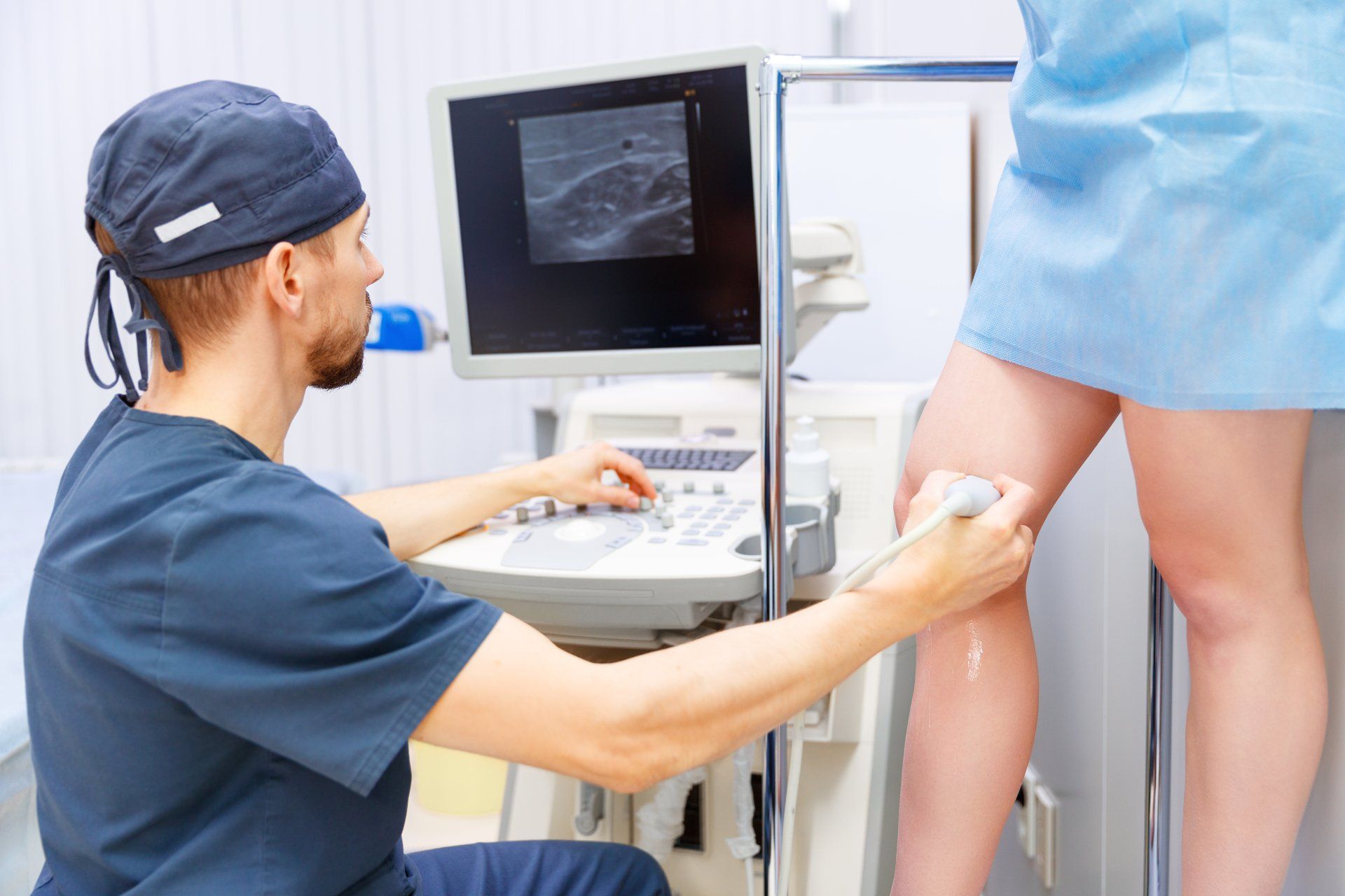 A doctor is examining a woman 's leg with an ultrasound machine.