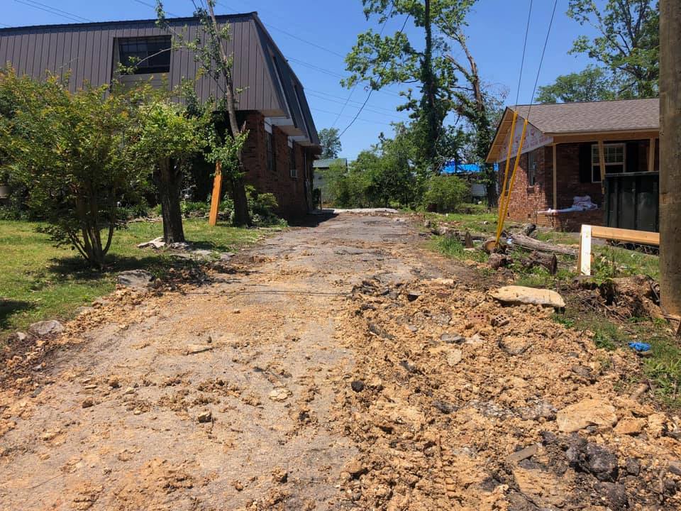 A dirt road with a house in the background
