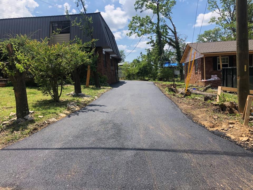 A newly paved road leading to a brick house.