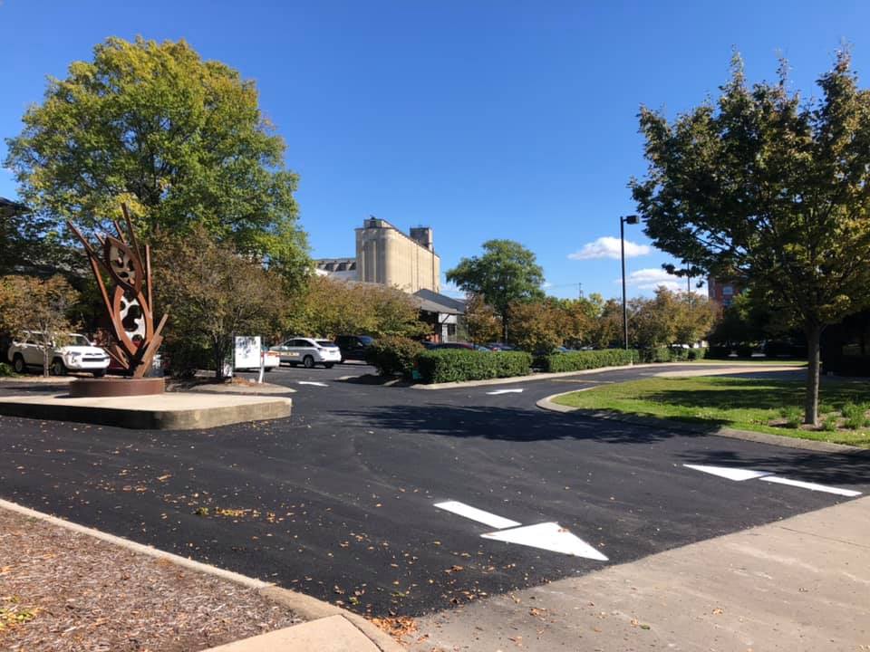 A parking lot with a statue in the middle of it and a building in the background.