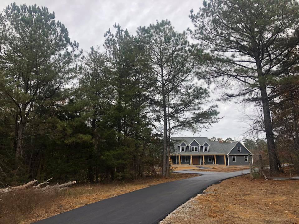 A house is sitting on the side of a road surrounded by trees.