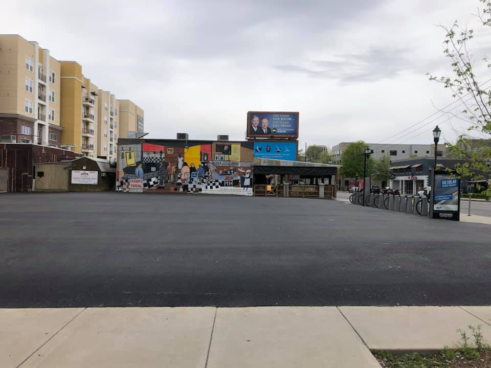 A parking lot with a mural on the side of it and a building in the background.