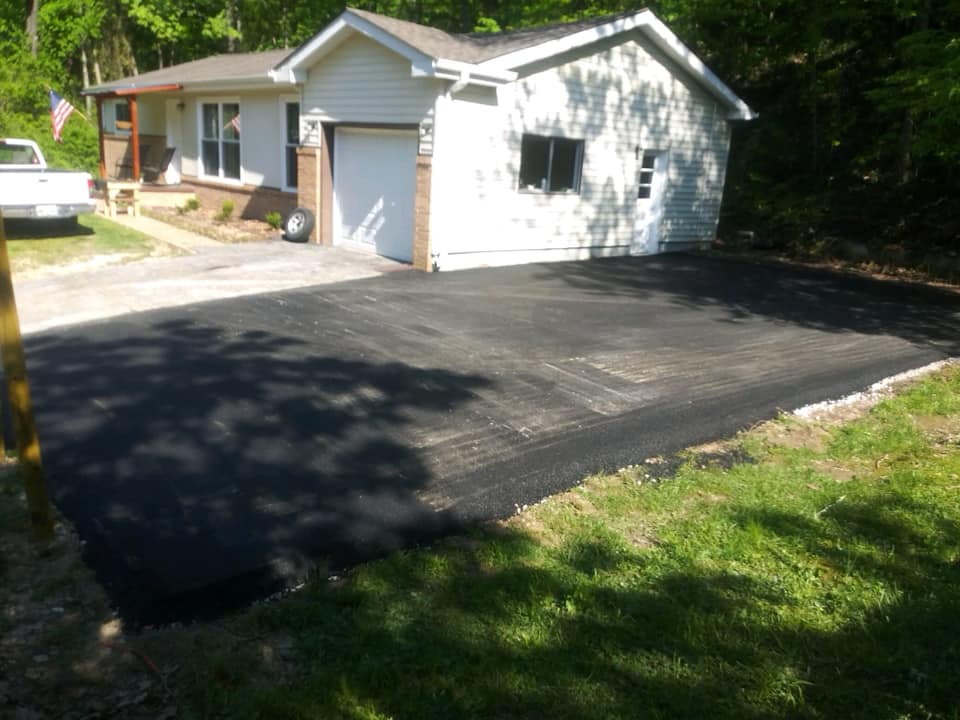 A white house with a black driveway in front of it