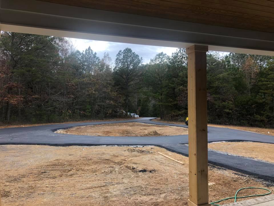 A view of a road from a porch with trees in the background.