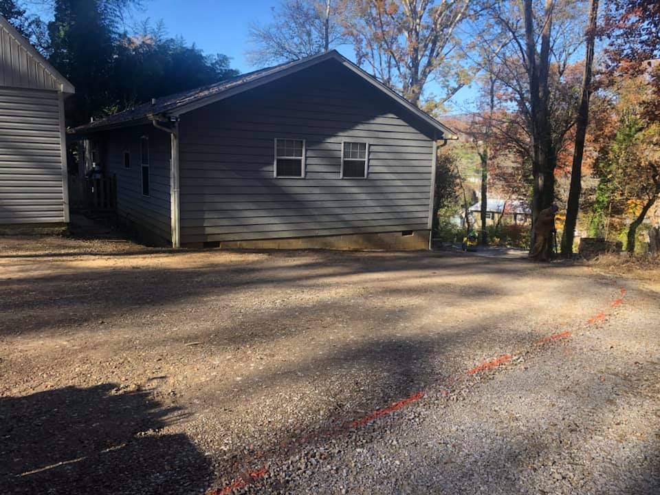 A house with a driveway in front of it and trees in the background.