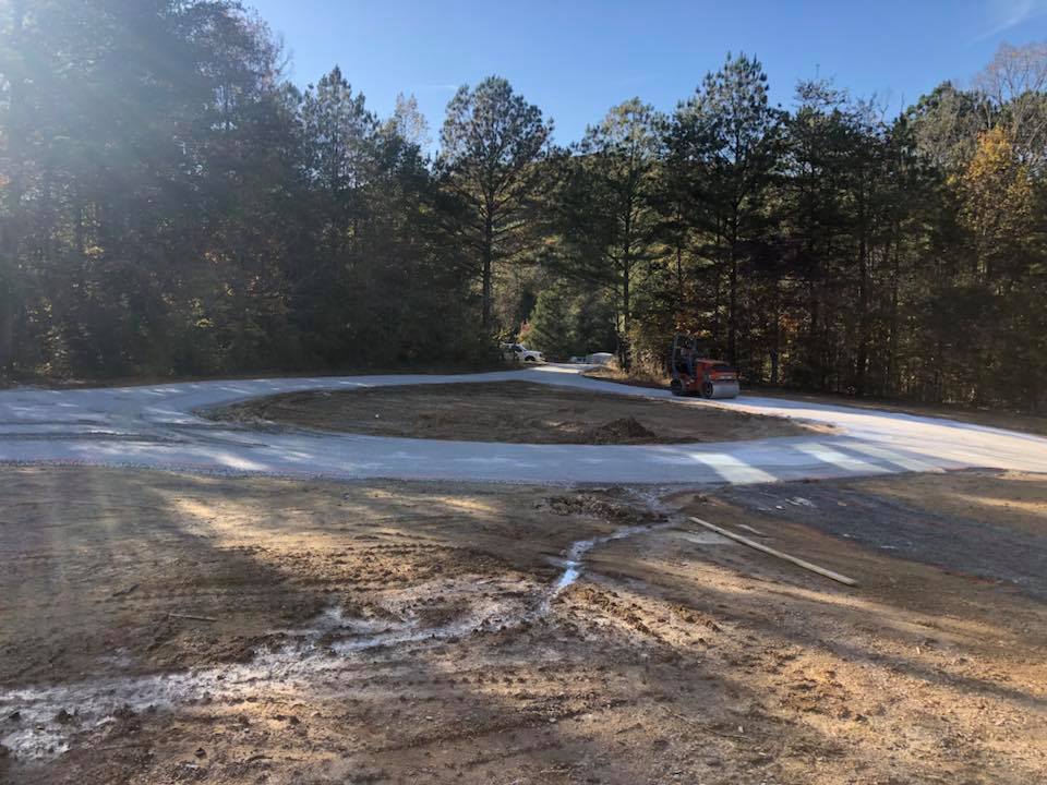 A car is driving down a dirt road in the woods.