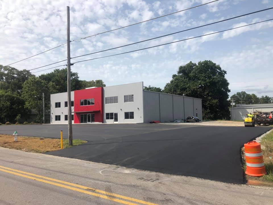 A large white building with a red trim is being built next to a road.